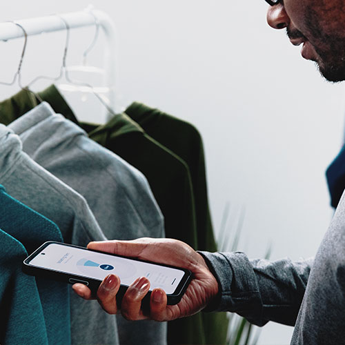 Ein Mann hält ein Zebra EM45 RFID Enterprise Mobile in der Hand vor einer Kleiderstange