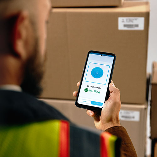 Ein Mann hält ein Zebra EM45 RFID Enterprise Mobile in der Hand vor Kartons