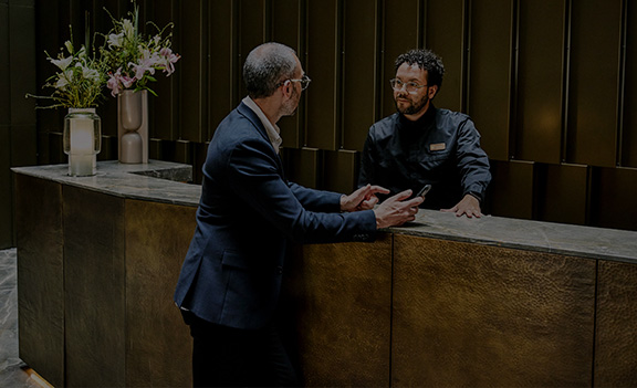 Zwei Männer unterhalten sich an der Rezeption eines Hotels